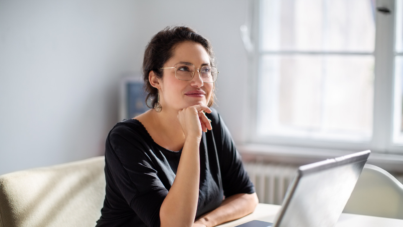 Immagine di una donna pensierosa mentre è davanti al computer