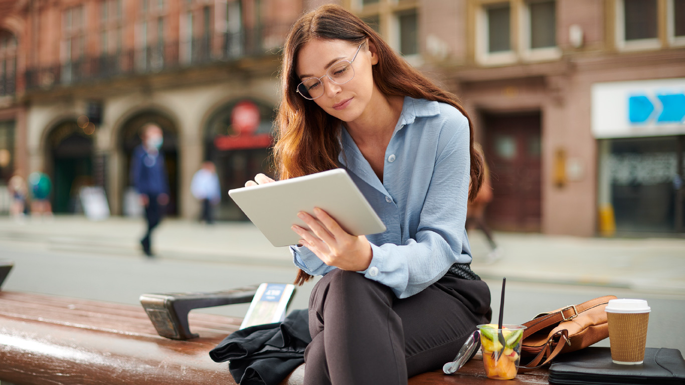 Immagine di una ragazza che, durante la pausa pranzo, legge le notizie sul tablet