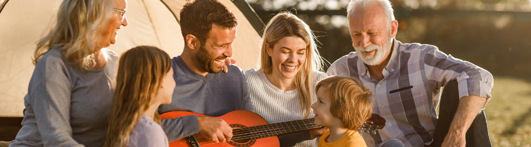 Immagine di nonni, figli e nipoti che si divertono seduti sul prato